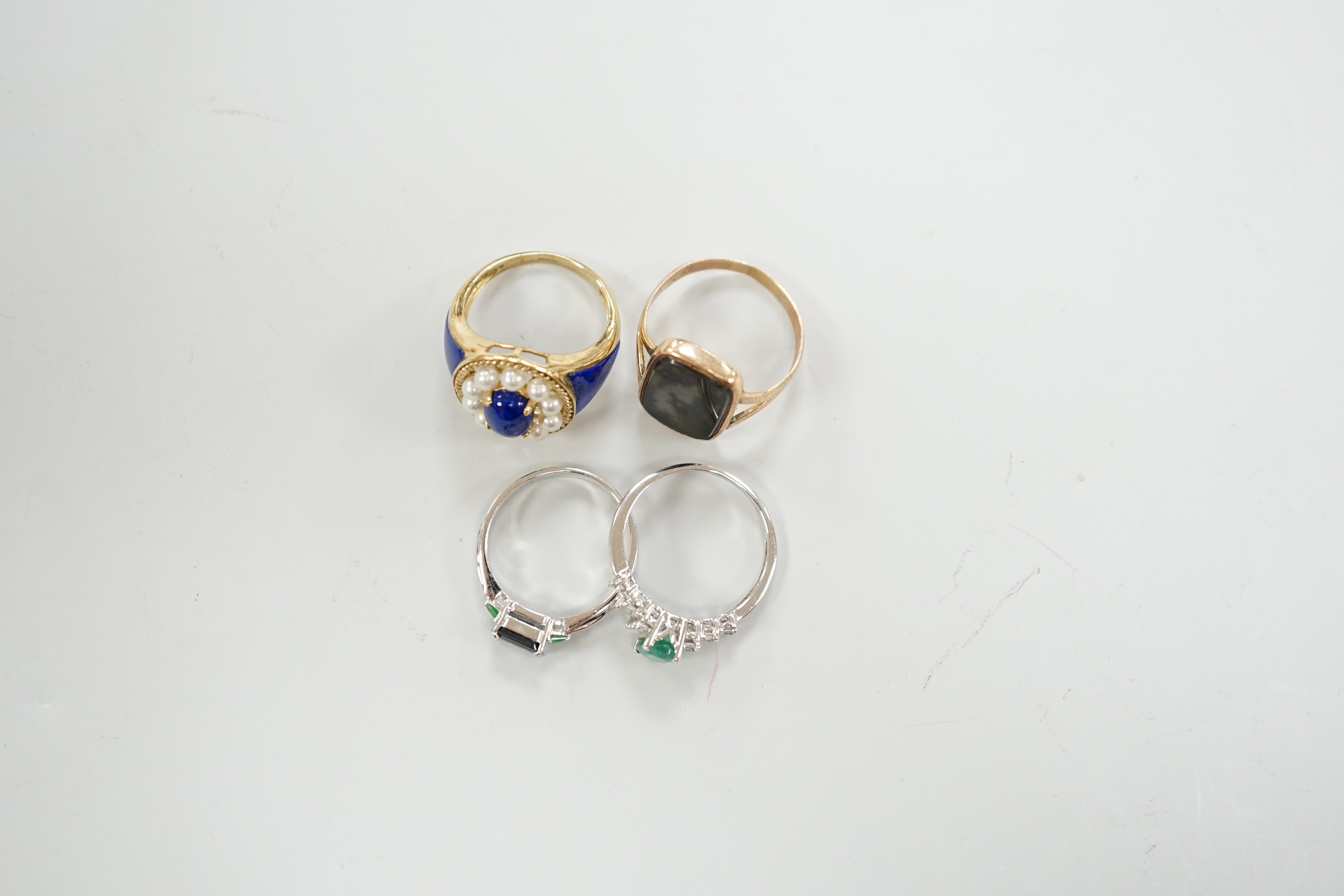 A modern 750 white metal and three stone gem set ring, two 9ct gold and gem set rings including lapis and seed pearl and one other yellow metal ring.